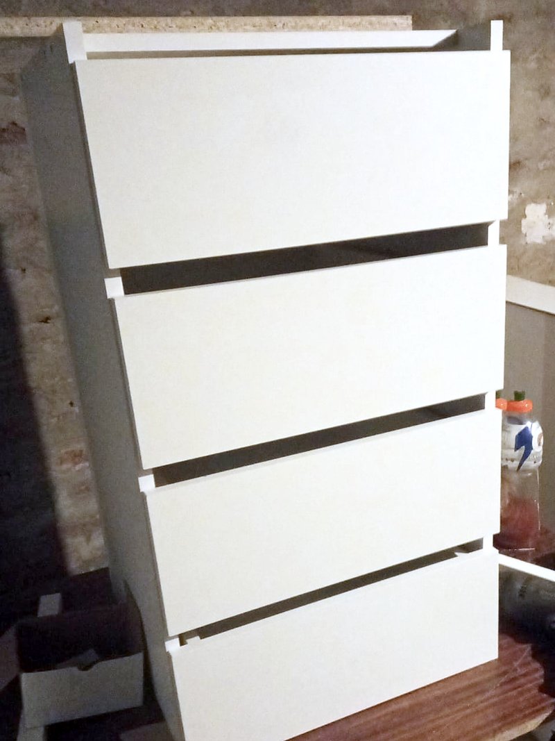 Cómoda blanca de melamina con cuatro cajones, recién armada en el taller