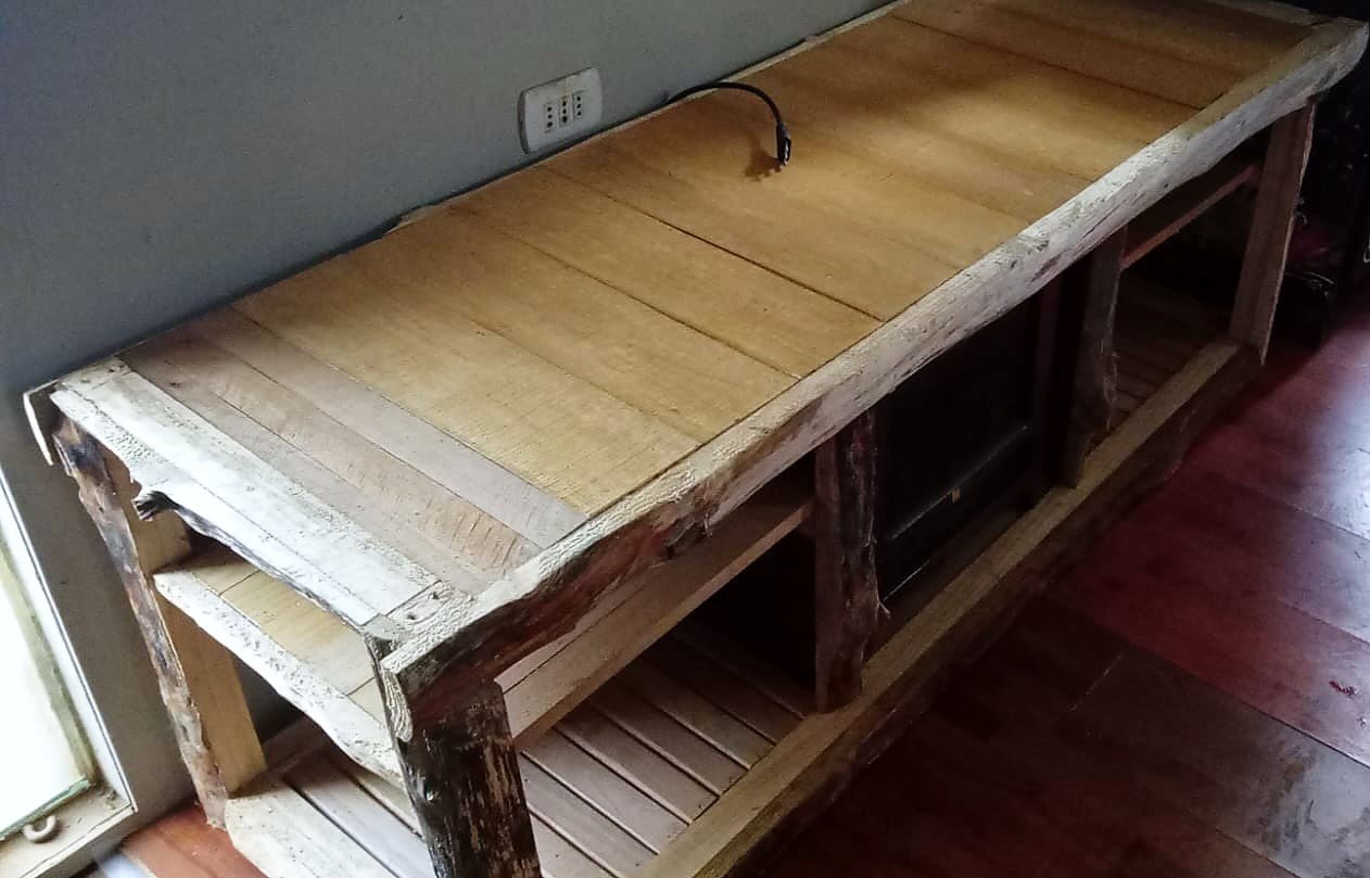 Rack bajo de madera rústica visto desde arriba: cubierta de tablas con borde de canto natural y repisas de listones